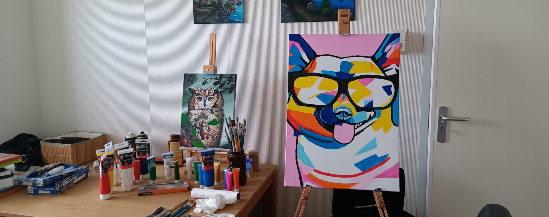 Foto van de atelier. Tafel vol acryl verf tubes en kwasten.